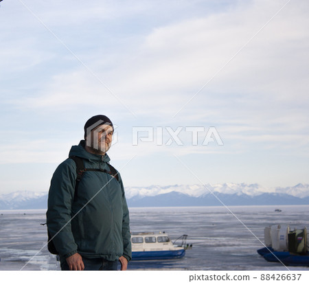 Portrait of a man in winter clothes against the background of the frozen Lake Baikal. Mountains. Hovercraft. Portrait of a man in winter clothes against the background of the frozen Lake Baikal. Mountains. Hovercraft. 88426637