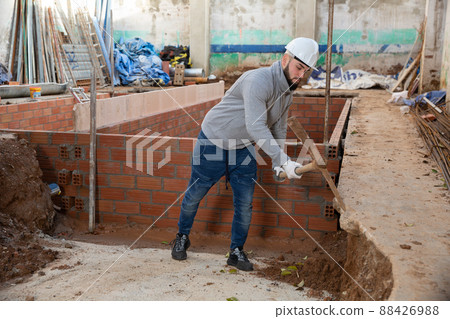 Guy excavating ground with mattock at building site Guy excavating ground with mattock at building site 88426988