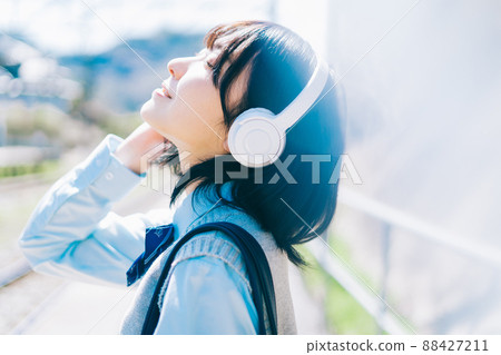 High school girl listening to music on the platform of the station 88427211