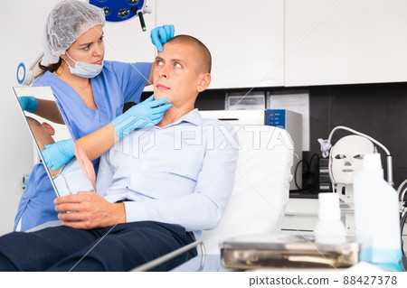 Woman beautician consulting male client before facial treatment Woman beautician consulting male client before facial treatment 88427378