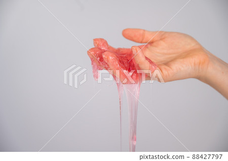 Red slime flowing down from a woman's hand on a white background. Red slime flowing down from a woman's hand on a white background. 88427797