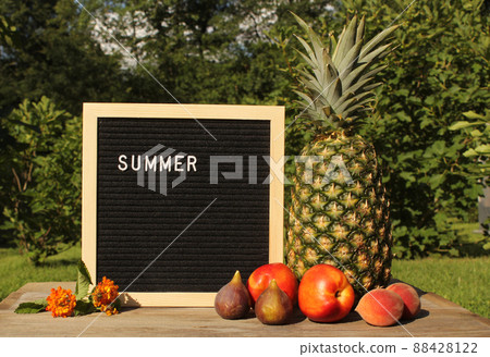 Fresh Pineapple outdoors with Apricots, Peaches and figs. sale sign garden in background 88428122