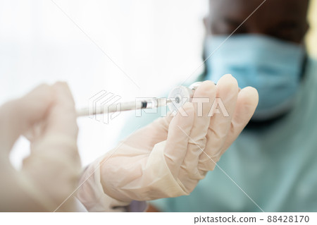 Selective focus of syringe, African American Wear a medical mask and being covid vaccinated for the prevention of coronavirus and flu. Concept of immunization from inoculation Selective focus of syringe, African American Wear a medical mask and being covid vaccinated for the prevention of coronavirus and flu. Concept of immunization from inoculation 88428170
