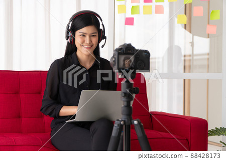 Vlog Asian woman blogger influencer sitting on the sofa in home and recording video blog for teaching and coach her Students or subscriber. Concept of the content creator online for a new lifestyle Vlog Asian woman blogger influencer sitting on the sofa in home and recording video blog for teaching and coach her Students or subscriber. Concept of the content creator online for a new lifestyle 88428173