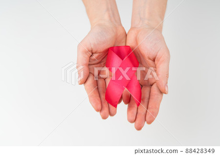 Female hands with a red ribbon on a white background. Symbol of the fight against AIDS. Copy space.  88428349