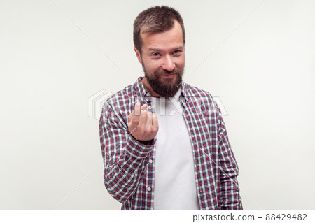 Come here sign. Portrait of friendly bearded man in casual plaid shirt inviting to approach doing beckoning gesture and looking playful flirtatious. indoor studio shot isolated on white background 88429482