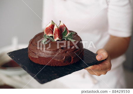 Lady is preparing dessert.Woman bakes a cake. Confectioner with chocolate cake. Lady is preparing dessert.Woman bakes a cake. Confectioner with chocolate cake. 88429550