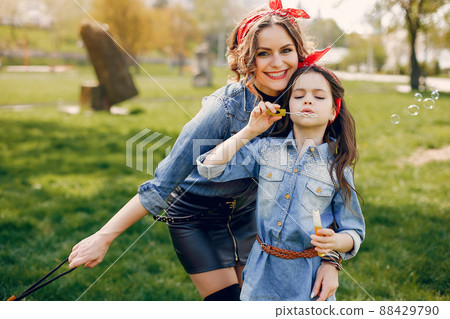 Fashionable mother with daughter. Family in a spring park. Woman in a blue shirt 88429790