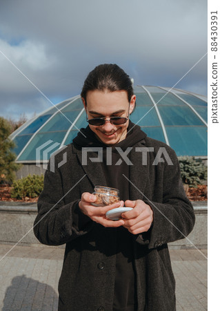 Young gay hipster eating peanuts at the street smiling happy sunglasses Young gay hipster eating peanuts at the street smiling happy sunglasses 88430391