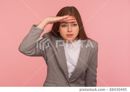Portrait of pretty young woman in business suit holding hand over eyes and looking far away with attentive view, being ambitious making business plans for successful future. studio shot isolated 88430495