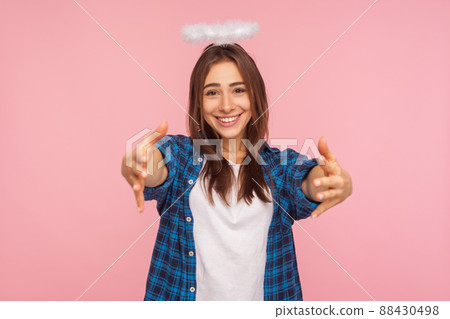 Portrait of kind positive girl with nimbus over head stretching arms to camera with friendly generous smile, going to embrace, sharing love and care. indoor studio shot isolated on pink background 88430498