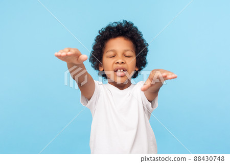 Portrait of blind little curly boy walking with closed eyes and outstretched hands, confused disoriented child with vision problems searching way. indoor studio shot isolated on blue background 88430748