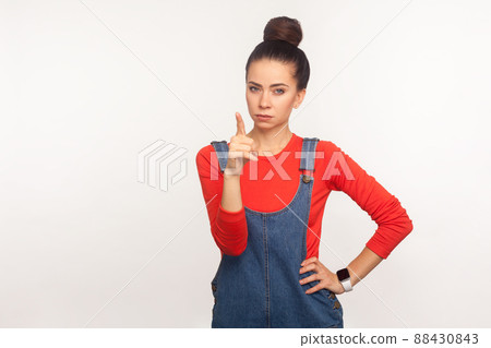 Hey you. Portrait of bossy angry girl with hair bun in denim overalls dispraising for bad behavior with admonishing finger gesture, scolding and teaching. studio shot isolated on white background Hey you. Portrait of bossy angry girl with hair bun in denim overalls dispraising for bad behavior with admonishing finger gesture, scolding and teaching. studio shot isolated on white background 88430843