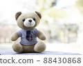 A brown teddy bear in a shirt and tie sits on a wooden background with a green background background. There is free space to insert a message. 88430868