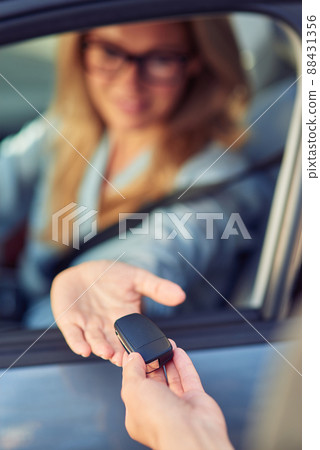 Male hand giving a car keys to woman sitting behind steering wheel, car purchase concept Male hand giving a car keys to woman sitting behind steering wheel, car purchase concept 88431356