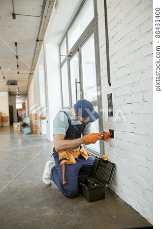 Electrician fixing power electric socket with screwdriver 88431400