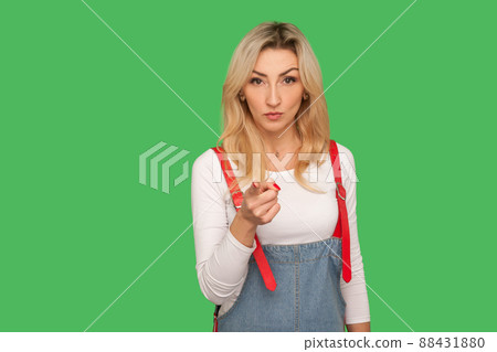 Hey, I'm warning you. Portrait of displeased angry adult blond woman in stylish denim overalls accusing with admonishing finger gesture, looking strict with dispraise. indoor studio shot, isolated 88431880