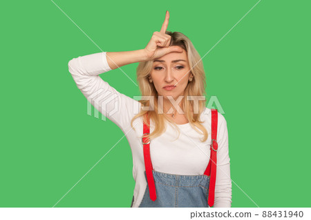 I lost job. Portrait of unlucky depressed adult woman in stylish denim overalls showing loser gesture, upset about unsuccess, crisis or failed project. indoor studio shot isolated on green background I lost job. Portrait of unlucky depressed adult woman in stylish denim overalls showing loser gesture, upset about unsuccess, crisis or failed project. indoor studio shot isolated on green background 88431940