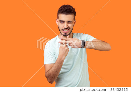 Hashtag. Portrait of joyous handsome brunette man with beard in casual white t-shirt making hash gesture and winking at camera, popular blog content. indoor studio shot isolated on orange background 88432315