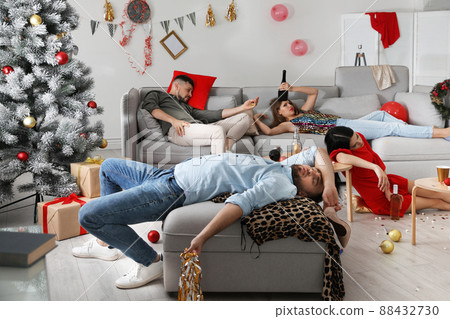 Friends suffering from hangover in messy room after New Year party 88432730