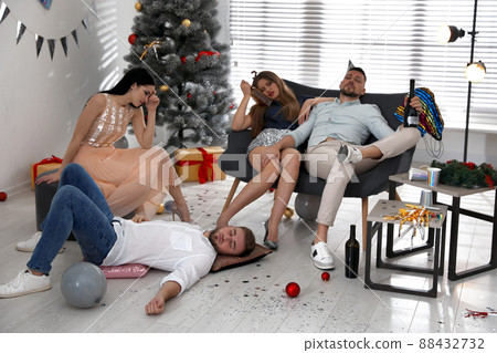 Friends suffering from hangover in messy room after New Year party Friends suffering from hangover in messy room after New Year party 88432732