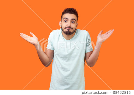 I don't know, who cares. Portrait of confused clueless brunette man with beard in white t-shirt shrugging shoulders, making no idea gesture, whatever. indoor studio shot isolated on orange background I don't know, who cares. Portrait of confused clueless brunette man with beard in white t-shirt shrugging shoulders, making no idea gesture, whatever. indoor studio shot isolated on orange background 88432815