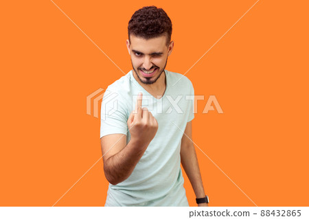 Come here. Portrait of handsome brunette man with flirtatious smile in casual white t-shirt winking and making beckoning gesture, inviting to approach. indoor studio shot isolated on orange background Come here. Portrait of handsome brunette man with flirtatious smile in casual white t-shirt winking and making beckoning gesture, inviting to approach. indoor studio shot isolated on orange background 88432865
