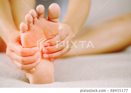 A woman suffering from feeling knee pain sitting sofa at home. hand massaging her painful knee. Health care and medical concept. 88435177