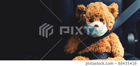 A brown teddy bear wearing a mask sits in the car. A brown teddy bear wearing a mask sits in the car. 88435416