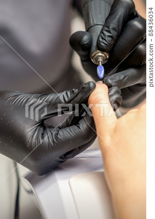 Manicure master uses electric nail file machine in a nail salon, close up Manicure master uses electric nail file machine in a nail salon, close up 88436034