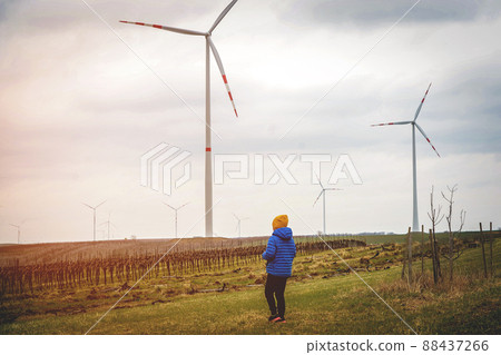 Future of kid is elternative energy. Kid on wind farm. Happy boy on vacation walking on nature. Renewable energies and sustainable resources wind mills. wind turbine. Sustainable climate visuals 88437266
