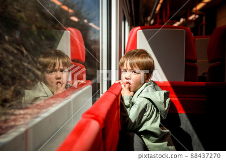 Little funny kid boy traveling in train looking outside the window. Little funny kid boy traveling in train looking outside the window. 88437270