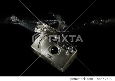 Camera underwater - sinking camera. Photography - an old camera immersed in water. Camera underwater - sinking camera. Photography - an old camera immersed in water. 88437520