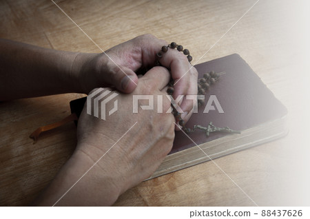 Hand holding Rosary on a Holy Bible praying. Christianity concept. 88437626