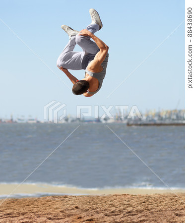 Upside down and downside up. An athletic young man doing a somersault at the beach. Upside down and downside up. An athletic young man doing a somersault at the beach. 88438690
