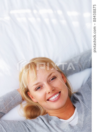 Woman relaxing on bed. Top view of pretty young woman lying on bed and smiling. 88438875