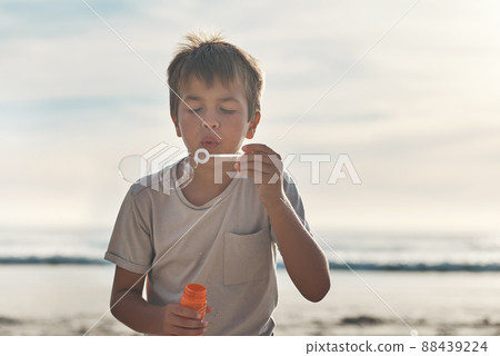 Out for some bubble fun. Cropped shot of a young boy standing alone and blowing bubbles during a day on the beach. 88439224