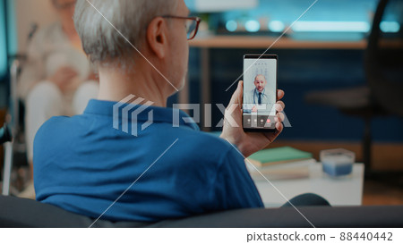 Elderly person calling doctor on videoconference to attend consultation, using mobile phone for telemedicine and telehealth. Retired adult talking to specialist on online remote video call. Elderly person calling doctor on videoconference to attend consultation, using mobile phone for telemedicine and telehealth. Retired adult talking to specialist on online remote video call. 88440442