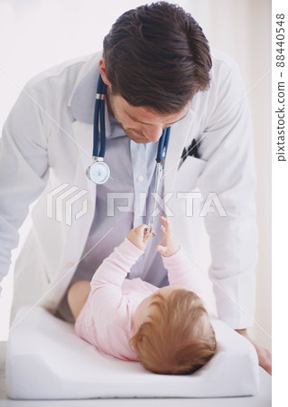 Meeting his little patient. A male doctor standing by an infant patient. 88440548