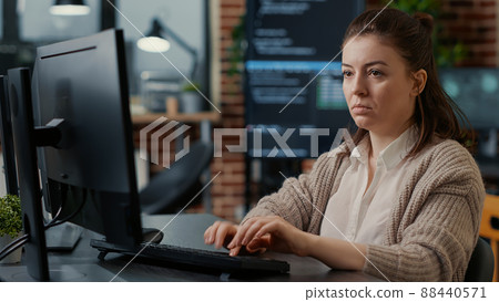 Database programer working focused looking at computer screen while typing in it startup office. App developer writing artificial intelligence code with algorithms compiling on screens in background. Database programer working focused looking at computer screen while typing in it startup office. App developer writing artificial intelligence code with algorithms compiling on screens in background. 88440571