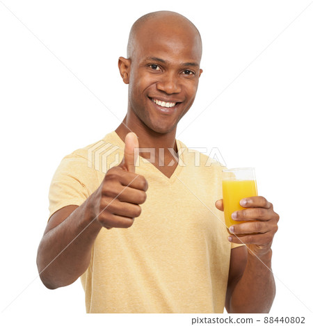 Keeping healthy. Studio shot of a handsome African-American man giving the thumbs-up while holding a glass of orange juice. 88440802