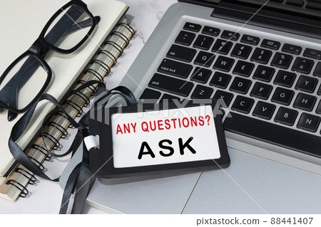 Any questions text written on red name tag placed on a laptop. 88441407