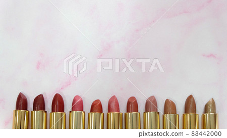 Flat lay of lipsticks in different hues of red lined up side by side, on a pink marble background. With copy space on the top part. Flat lay of lipsticks in different hues of red lined up side by side, on a pink marble background. With copy space on the top part. 88442000