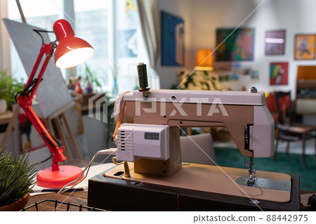 Horizontal no people selective focus shot of sewing machine and lamp on table in living room belonging to fashion designer Horizontal no people selective focus shot of sewing machine and lamp on table in living room belonging to fashion designer 88442975