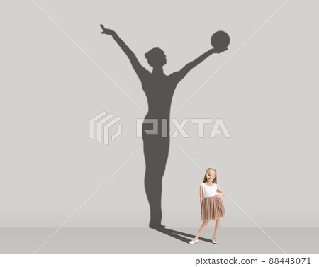 Kids and future. Conceptual image with little girl dreaming about becoming gymnast isolated on studio gray wall. Focus on shadow 88443071