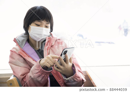 A child taking a break by operating a smartphone at a ski resort rest house A child taking a break by operating a smartphone at a ski resort rest house 88444039