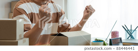 Online shopping concept the online salesperson having cheerful facial expression while setting his goods into the box Online shopping concept the online salesperson having cheerful facial expression while setting his goods into the box 88446441