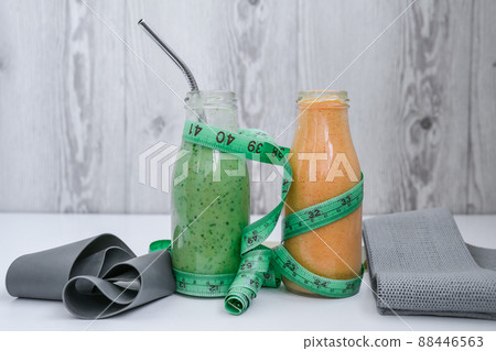 Seasonal Matcha green vegan smoothie and pumpkin carrot smoothie drink detox Breakfast with measuring tape and rubber resistance band. Stretch fitness band. Clean eating, weight loss, healthy dieting 88446563