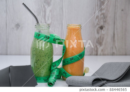 Seasonal Matcha green vegan smoothie and pumpkin carrot smoothie drink detox Breakfast with measuring tape and rubber resistance band. Stretch fitness band. Clean eating, weight loss, healthy dieting Seasonal Matcha green vegan smoothie and pumpkin carrot smoothie drink detox Breakfast with measuring tape and rubber resistance band. Stretch fitness band. Clean eating, weight loss, healthy dieting 88446565
