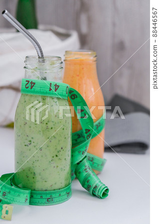 Seasonal Matcha green vegan smoothie and pumpkin carrot smoothie drink detox Breakfast with measuring tape and rubber resistance band. Stretch fitness band. Clean eating, weight loss, healthy dieting 88446567